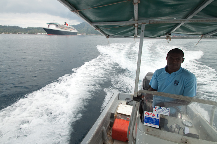 I hired a boat for a few hours, to see the harbor and the volcanos up close. John is driving, and in the background is the QM2.